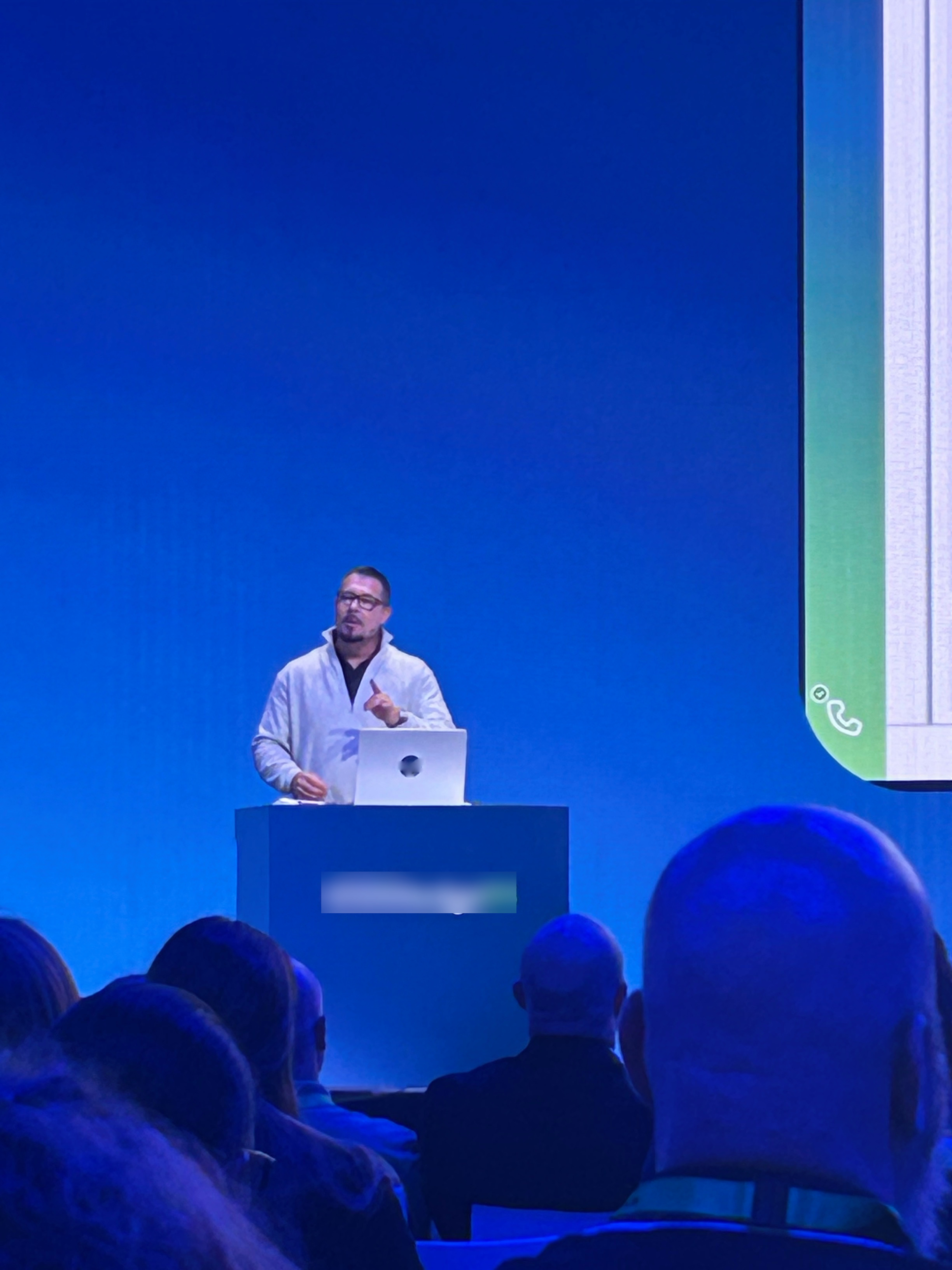 Chad Corriveau presenting at ServiceNow Knowledge25 conference main stage, dramatic blue lighting